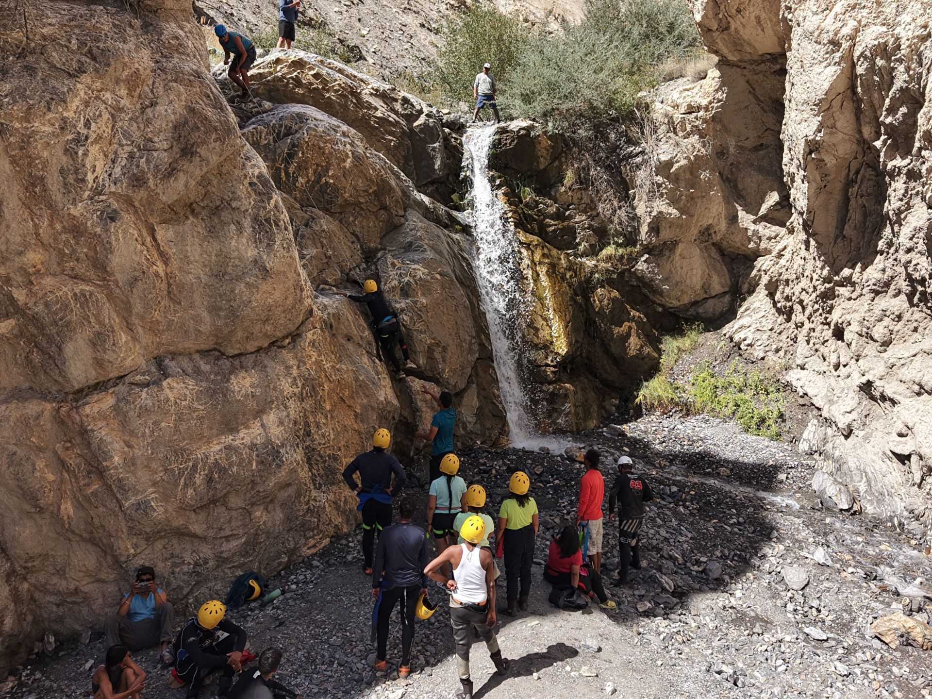 Helmeted expedition guests exploring a rocky waterfall beside their guides