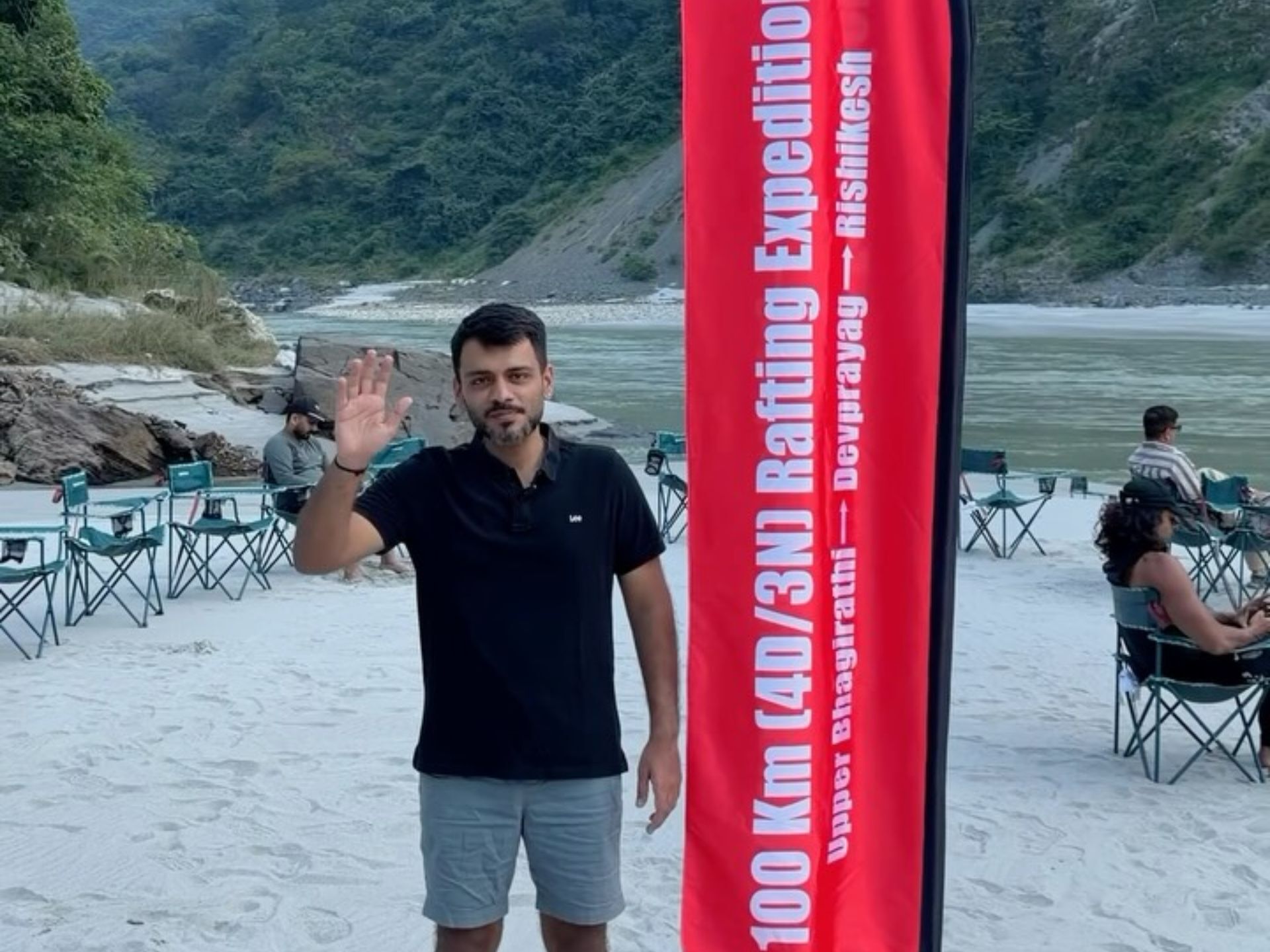 A Globesome guest beside the 100 km expedition flag at a riverside camp