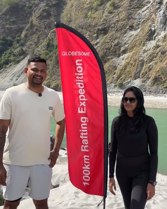 Guests with the Globesome rafting expedition flag by the Ganga in Rishikesh