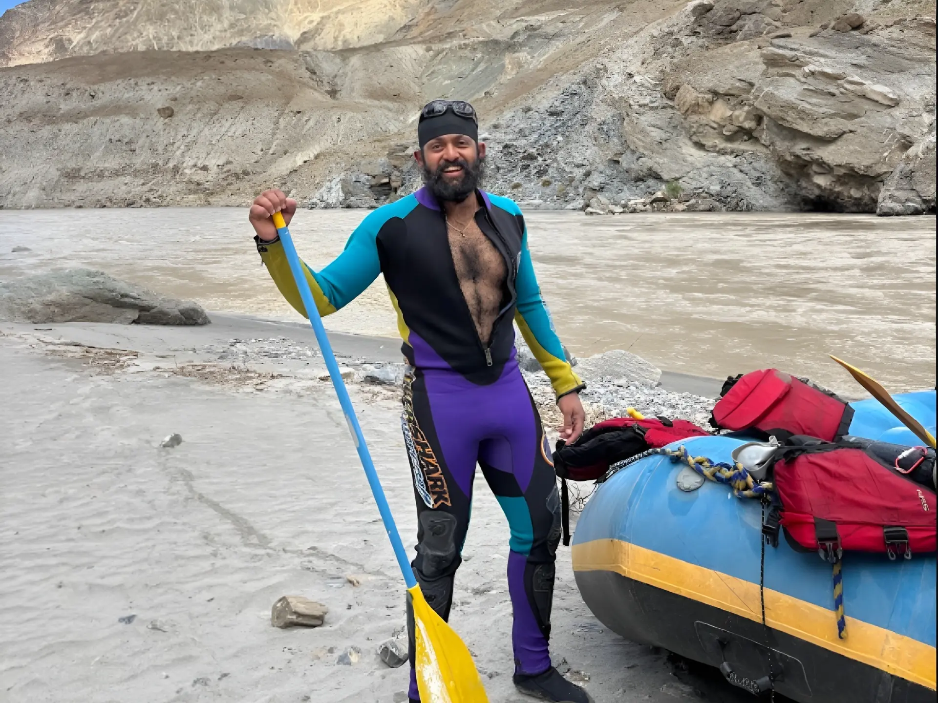 Zanskar River expedition guide with paddle beside a loaded raft in Ladakh